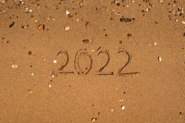 está dibujando en la arena de una playa con una ola junto al mar vacaciones en el mar concepto de año nuevo