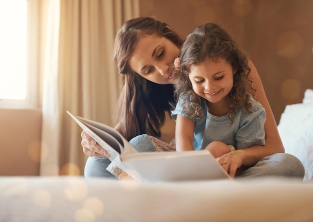 Esta é a melhor história de sempre Foto de uma mãe e filha felizes em casa lendo um livro de histórias na cama