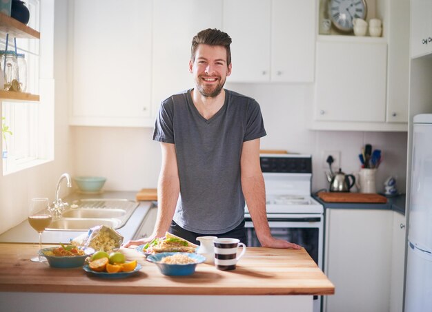 Esta é a minha dieta para o dia retrato de um jovem bonito em frente às refeições que ele preparou em sua cozinha