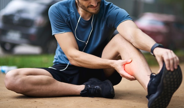 Esta lesão exige um tempo limite Foto de um jovem esportivo segurando sua panturrilha com dor enquanto se exercita ao ar livre