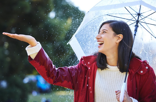 Está lloviendo fuerte Toma de una mujer joven de pie bajo la lluvia con un paraguas