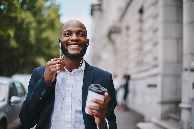 Esta pausa para o café me fez sentir inspirado novamente Foto de um empresário segurando um café e ouvindo música através de fones de ouvido enquanto caminhava pela cidade