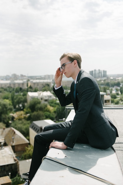 Está posando un hombre con traje gris y corbata azul.