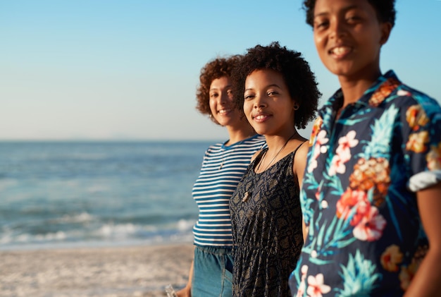 Estábamos juntos en esta vida Retrato de un atractivo joven trío de mujeres juntas y posando en la playa durante el día
