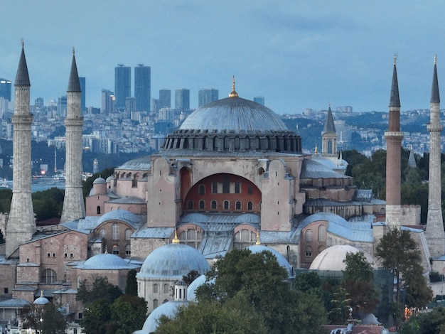 Estabelecimento de uma foto aérea de uma Grande Mesquita de Hagia Sophia com a Ponte do Bósforo e o horizonte da cidade com uma bandeira no fundo em Fatih, Istambul, Turquia, ao pôr do sol