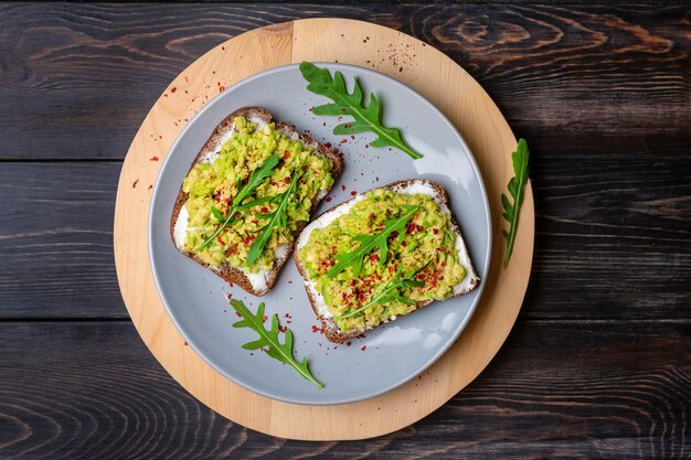 Foto establecer sándwiches para el desayuno - rebanada de pan integral oscuro, guacamole sobre mesa de madera