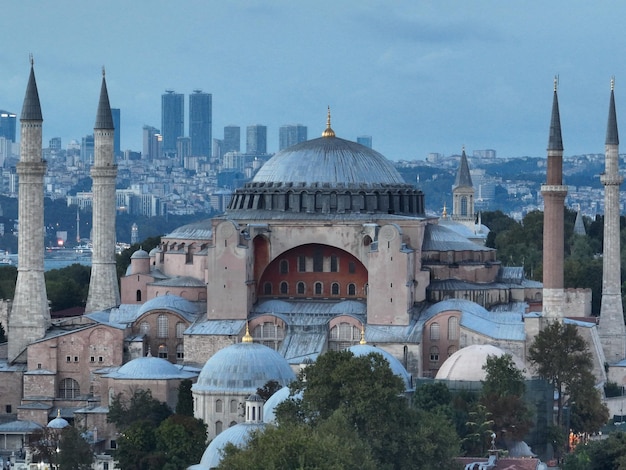 Estableciendo una toma de un dron aéreo en órbita de una Santa Gran Mezquita de Hagia Sophia con el puente del Bósforo y el horizonte de la ciudad con una bandera en el fondo en Fatih Estambul Turquía al atardecer