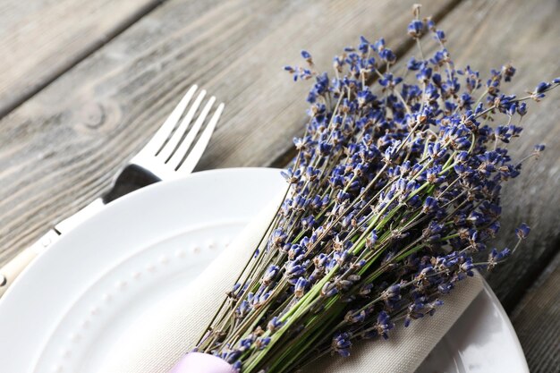 Establecimiento de la mesa de comedor con flores de lavanda en fondo de mesa de madera