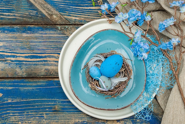 Establecimiento de la mesa de Pascua con huevos nido de pájaro y rama en flor