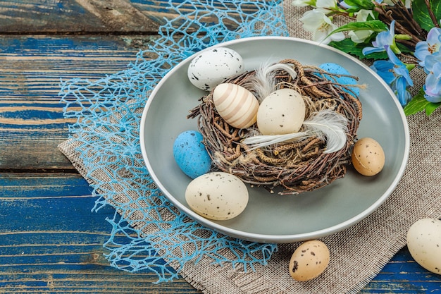 Establecimiento de la mesa de Pascua con huevos nido de pájaro y rama en flor