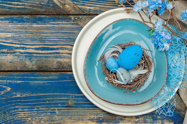 Establecimiento de la mesa de Pascua con huevos nido de pájaro y rama en flor