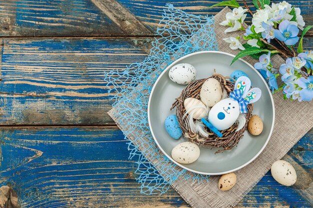 Establecimiento de la mesa de Pascua con huevos nido de pájaro y rama en flor