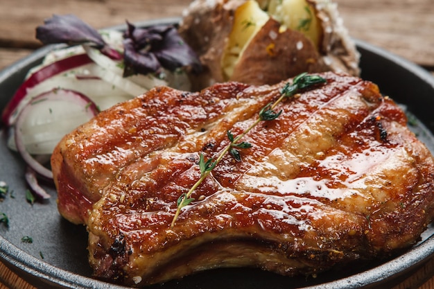 Estaca de beaf jugosa a la parrilla servida con patatas al horno y aros de cebolla, vista de cerca. Cocina americana.