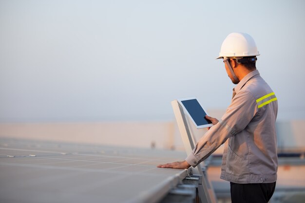 Estação de painéis solares fotovoltaicos de engenheiro verifica com computador tablet. conceito de tecnologia de energia