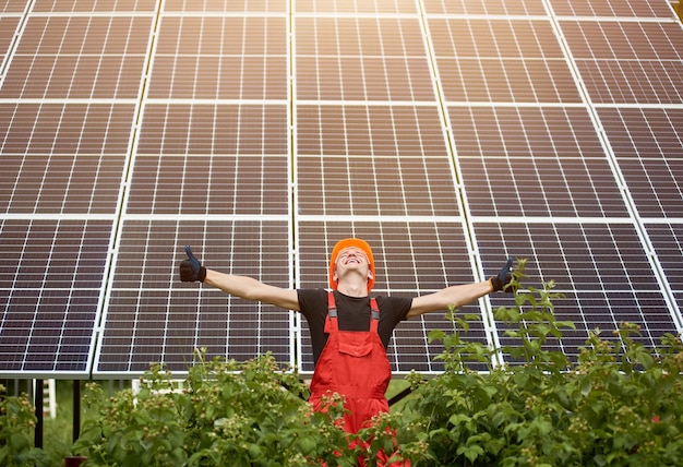 Estação solar de trabalho feliz levantando as mãos em um fundo de painéis fotovoltaicos