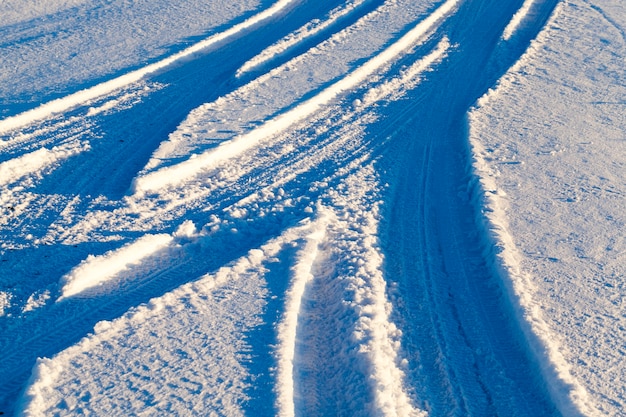 estacas lisas e curvas das rodas de carros na neve em uma estrada com neve, uma foto de um close-up de uma encruzilhada sob a neve