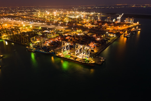 Estación de carga para la exportación internacional e importación por barco con contenedores en alta mar por la noche.