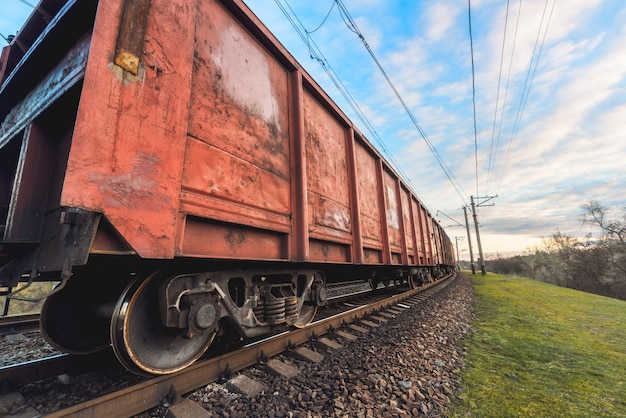 Estación de ferrocarril con vagones de carga y tren al atardecer