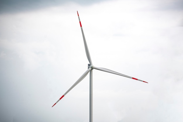 Una estación de molino de viento de electricidad de energía blanca contra el cielo nublado oscuro de fuertes lluvias