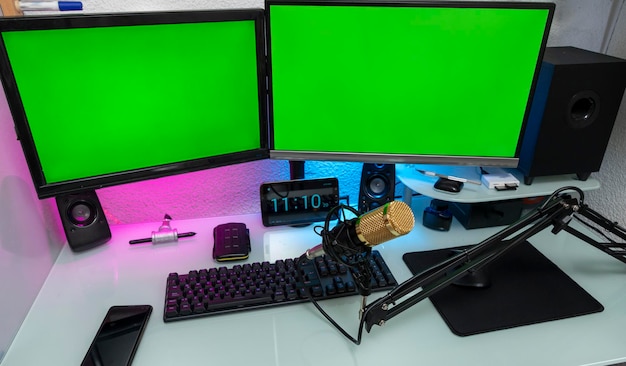 Foto estación de trabajo con micrófono y monitores con pantalla verde para montaje