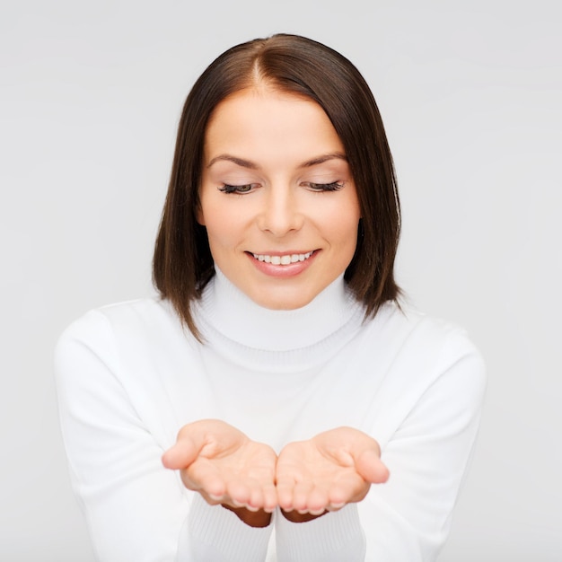 estacional, gente, concepto de felicidad - mujer sonriente en ropa de invierno con algo en las palmas