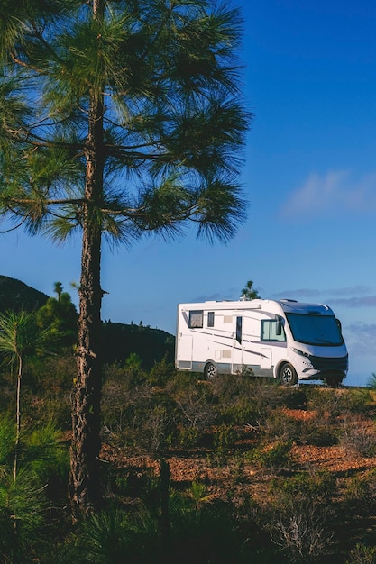 Foto estacionamento de caravana moderna na natureza com árvores e montanhas ao redor para acampamento de parque gratuito casa de jardim alternativa e destino para férias de férias vivendo sozinho viajante fora da rede