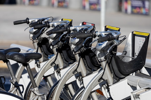 Estacionamiento en la calle con bicicletas con canastas para alquilar bajo el sol brillante