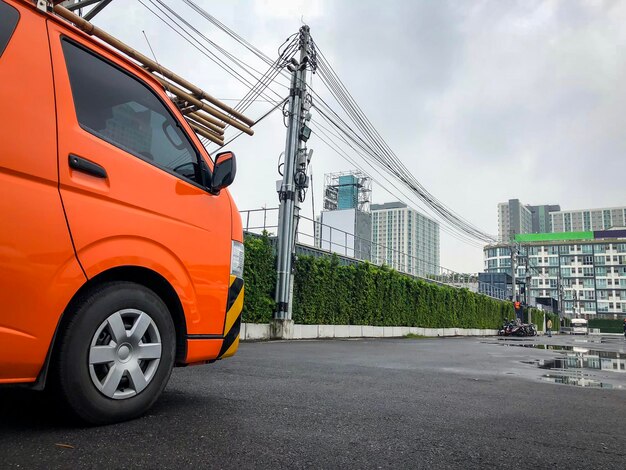 Estacionamiento de camioneta naranja eléctrica de empresa privada en el estacionamiento exterior esperando servicios eléctricos.