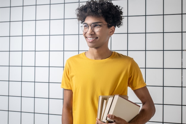 El estado de ánimo alegre. Chico joven afroamericano en anteojos sonriendo y mirando alegre