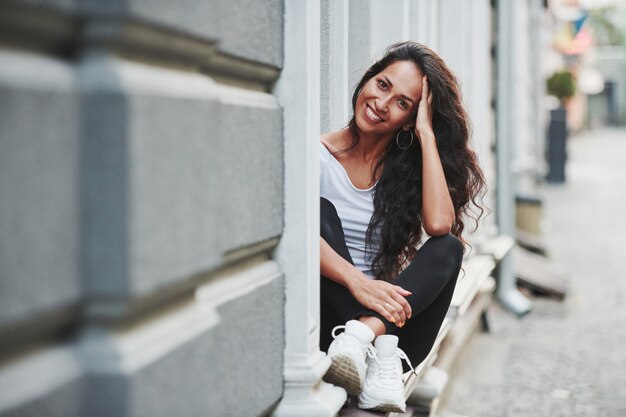 El estado de ánimo alegre. Hermosa mujer con cabello negro rizado tiene buen tiempo en la ciudad durante el día.