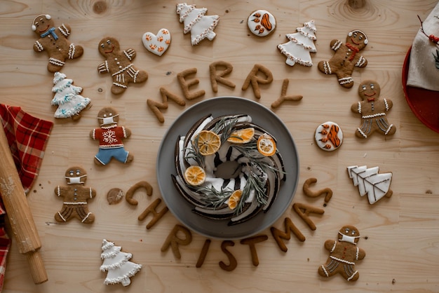 Estado de ánimo de celebración de Navidad. Pastel de Navidad casero tradicional sobre una mesa de madera con pan de jengibre y galletas en forma de cartas de feliz Navidad