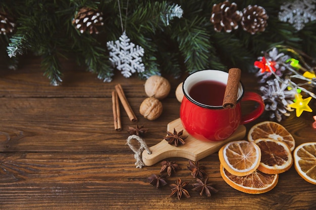 Foto el estado de ánimo navideño, la atmósfera navideña, la taza roja de café, las ramas de abeto con conos.