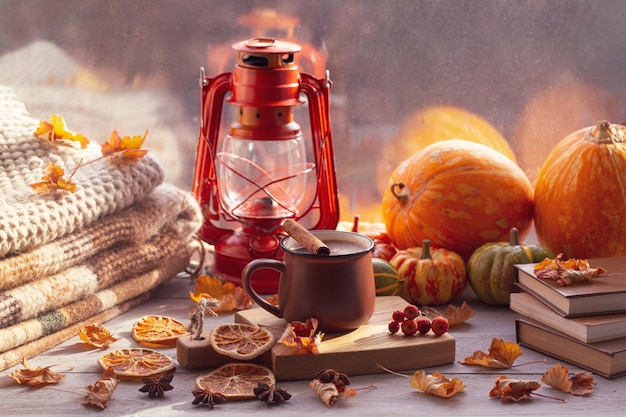 Estado de ánimo otoñal atmósfera otoñal Una taza de café calabazas una linterna mantas cálidas tejidas libros hojas de otoño en el alféizar de la ventana