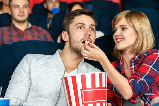 Estado de ánimo romántico. Retrato horizontal de una hermosa y feliz pareja joven compartiendo palomitas de maíz en el cine