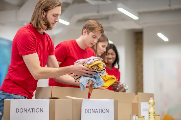 Estado de ánimo de trabajo. Participaron voluntarios serios de niños y niñas que doblaron cuidadosamente la ropa de donación en cajas de cartón