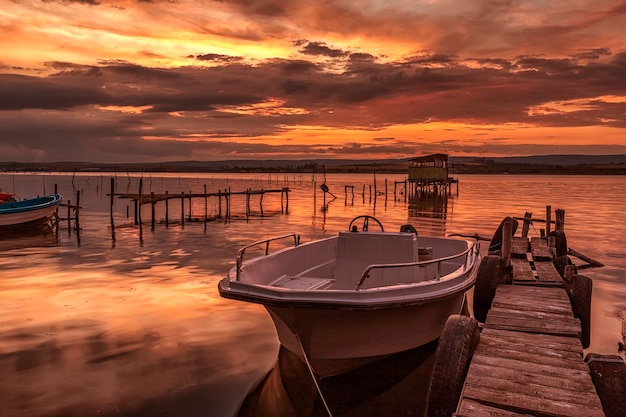 Estado de ánimo y tranquilidad en la orilla de un lago con un barco en un muelle de madera