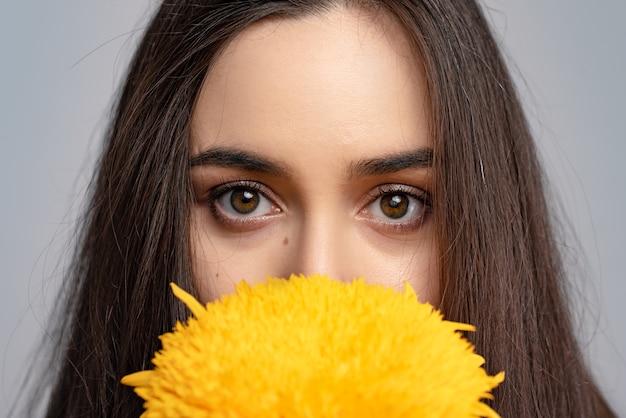 Estado de ánimo de verano. Hermosa mujer joven en vestido bonito sosteniendo flores delante de sus ojos