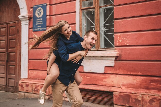 El estado feliz de una pareja joven en el contexto de una pared roja, la niña saltó sobre el chico