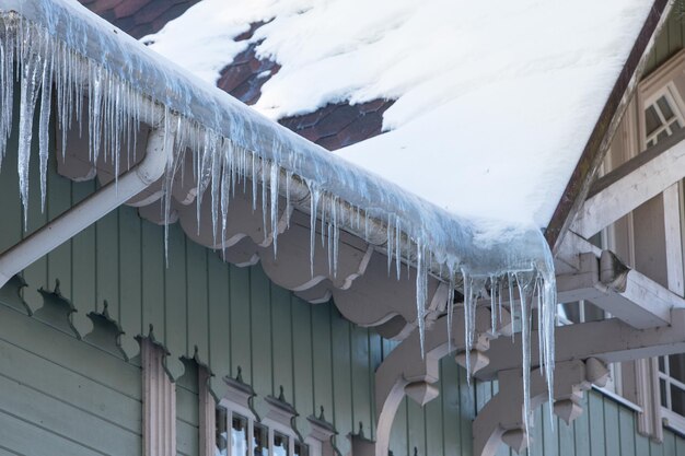 Estalactita de gelo pendurada do telhado com edifício de parede de madeira coberto com grandes icículas