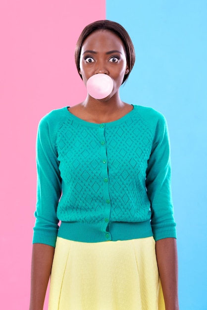 Estallido de colores Foto de estudio de una mujer joven y atractiva que sopla una burbuja de chicle contra un fondo de colores