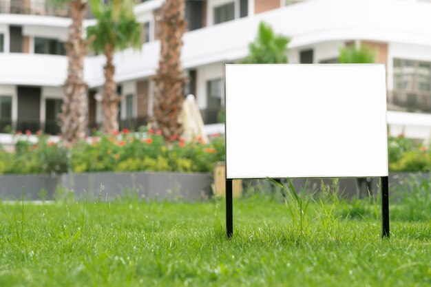 Estampa de publicidad vacía estandarte en el césped cerca de la acera en el parque verde de la ciudad espacio de copia para tex