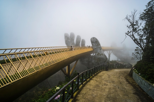 Estância de montanha ba na hill, cidade de danang, vietname. a ponte dourada é erguida por duas mãos gigantes na estância turística de ba na hill em um dia de neblina em danang, vietnã.