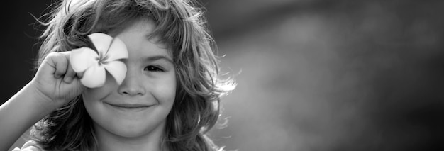 Foto estandarte con cara de niño de primavera retrato en primer plano de un niño pequeño rubio ojos plumeria flor niños divertidos