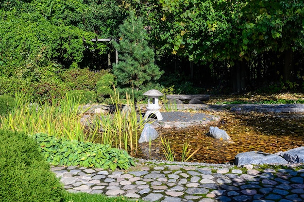 Estanque de jardín japonés y parque botánico de linternas a principios de otoño Día soleado de otoño