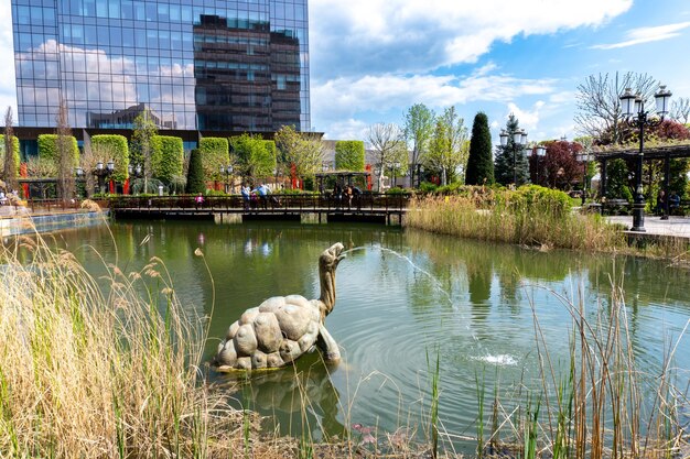 Un estanque con una tortuga y un edificio al fondo.