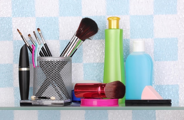 Foto estante con cosméticos y artículos de tocador en el baño