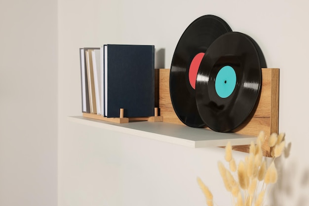 Estante de madera con discos de vinilo y libros sobre pared blanca.