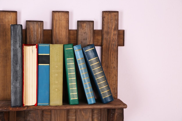 Estante de madera con libros en primer plano de la pared