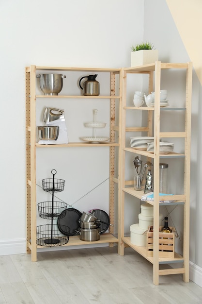 Estanterías de madera con utensilios de cocina cerca de la pared de color Interior elegante de la habitación