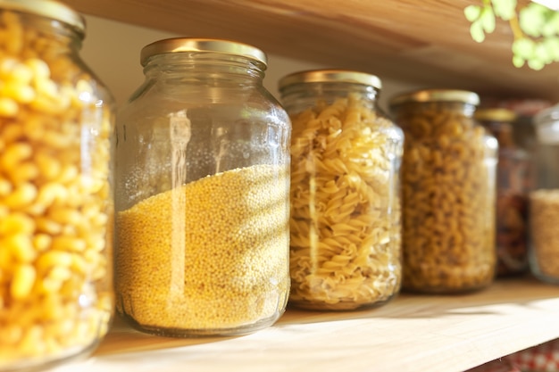 Estantes de madera en la despensa para el almacenamiento de alimentos, productos de grano en frascos de almacenamiento.